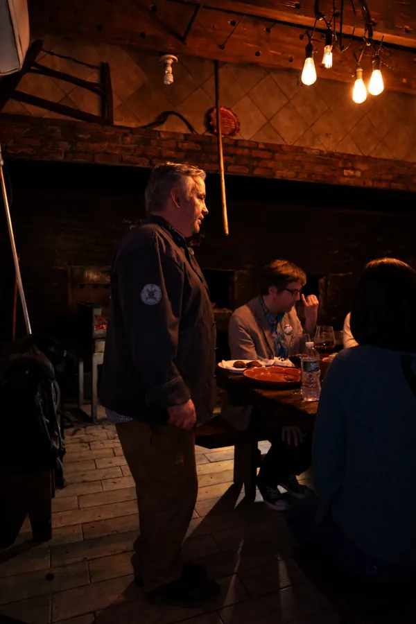 Don Rodrigo addressing guests beside the hearth